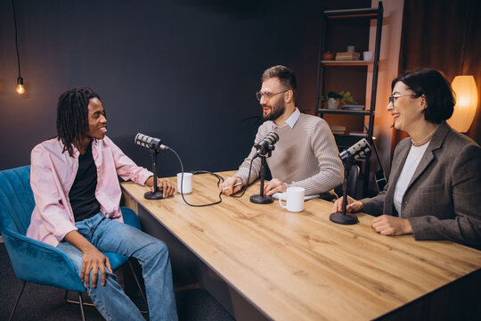 Podcasters talking during a recording session, using professional microphones and audio equipment in a modern studio
