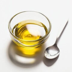 Clear glass bowl filled with yellow cooking oil, beside a spoon