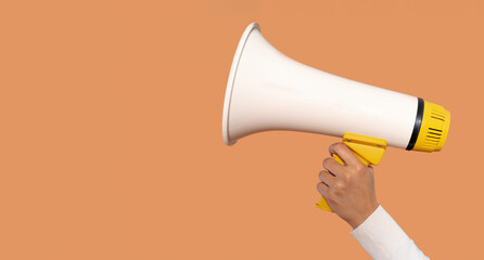 Individual holding a megaphone in front of an orange background while promoting an event or calling...