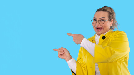 Cheerful woman in yellow coat gestures enthusiastically against a bright blue background,...