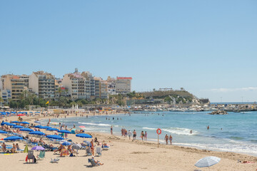 Poniente beach of Benidorm, full of people relaxing, sunbathing, swimming, and truly enjoying their vacation. Benidorm is popular resort city on Costa Blanca, in province of Alicante, Spain