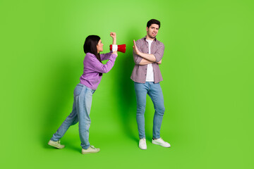 Young couple arguing playfully during a fun moment on a vibrant green background, expressing...