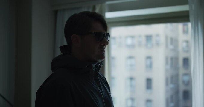 Steady cam around man standing still in hotel with sunglasses on - medium shot