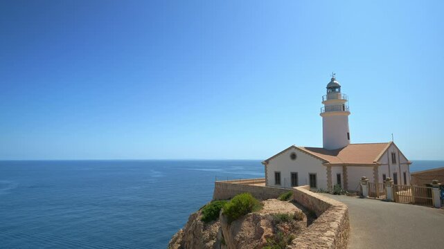 White capdepera lighthouse on rocky cliff overlooking calm blue sea, offering breathtaking scenic view in mallorca, balearic islands