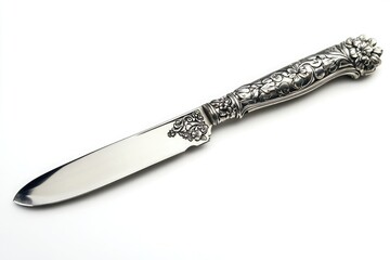 Close up of an ornate silver knife with floral designs on the handle on a white background surface