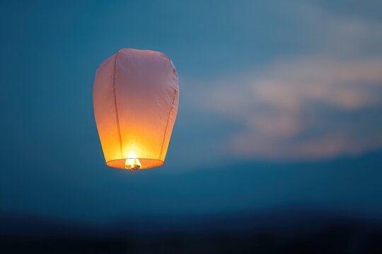 serene close-up of single glowing lantern floating in tranquil twilight sky representing peaceful and spiritual celebration