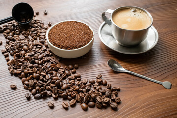 coffee beans, a cup of espresso and ground coffee on brown background