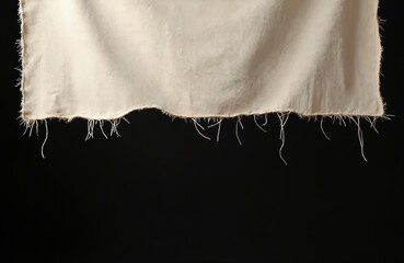 Torn beige fabric with frayed edges isolated on black background. Rough textile material with visible threads. Hole in the tissue. Vintage damaged clothes. Grunge background for design, textures.