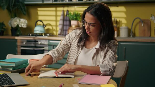 Indian woman businesswoman Hispanic latina girl gen z teen high school student freelancer at home kitchen drawing divider writing notebook draft notes study university pupil online studying homework