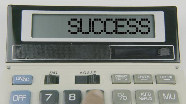 "Success" text displayed on a calculator's LED screen as a hand types numbers, symbolizing the achievement of financial goals and the culmination of planning, effort, and strategic decision-making