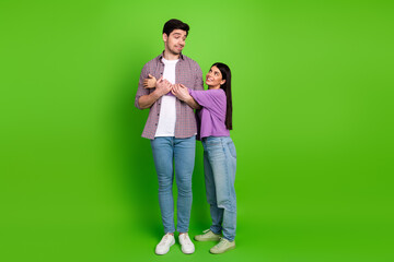 Happy couple enjoying playful bonding on a vibrant green background, showcasing love and joyful connection in casual and relaxed attire