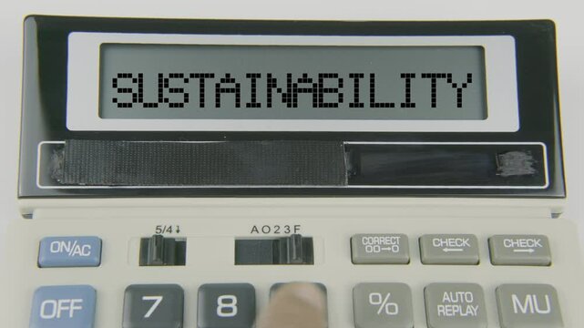 "Sustainability" text displayed on a calculator's LED screen as a hand types numbers, symbolizing environmentally and economically responsible financial planning and decision-making