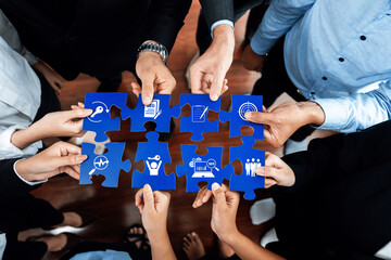 A diverse business team coming together, each person holding a puzzle piece, symbolizing...