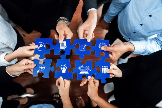 A diverse business team coming together, each person holding a puzzle piece, symbolizing collaboration, strategy, and problem-solving in a corporate setting. Amity - Powered by Adobe