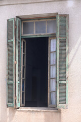 Fototapeta premium Weathered wooden window frame amidst a sunlit wall invites curiosity and wonder in a quiet neighborhood