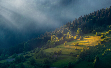 The magic rays of sunlight through the mist over mountain green hills.