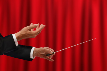 Conductor with baton against elegant red curtain, closeup. Space for text