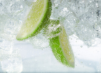 Soda water with lime slices and ice cubes, closeup