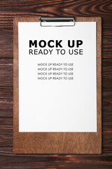 Clipboard with sheet of paper on wooden background, top view. Mockup Ready To Use