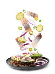 Tasty bruschettas with herring and flying ingredients on white background