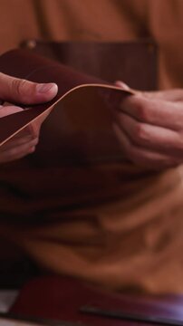 Master bends and turns leather detail of craft accessory in workshop close view. Leather goods manufacturer makes original item in studio. Manual work industry
