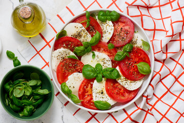 Traditional Italian caprese salad with tomatoes, mozzarella and basil on a white plate