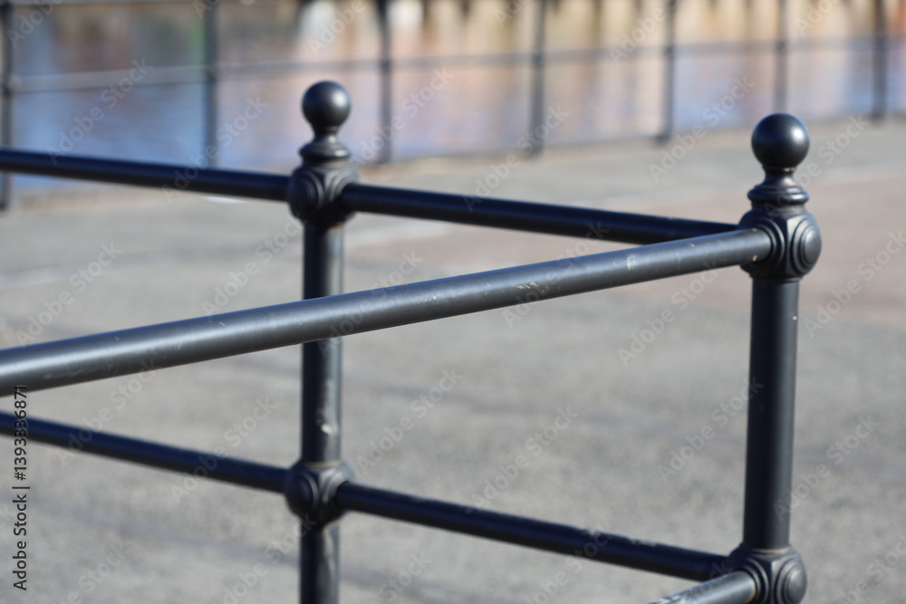 Poster A close-up shot of a metal fence with a body of water in the background, perfect for use as a decorative element or to add a touch of tranquility to your design.