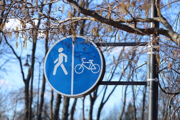 A person rides a bike in front of a blue street sign, providing a clear directional guide.