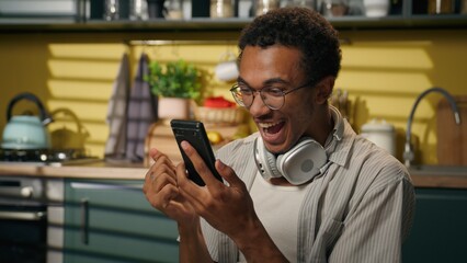 African American man happy businessman approval message smartphone win online game betting gambling shocked excited male guy freelancer student using mobile phone victory scream success prize at home