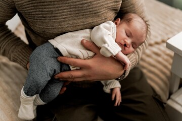 A tender moment between a father and his newborn baby, both lying on a soft surface. The father is...