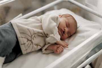 A sleeping newborn baby with congenital defect of cleft lip and palate wrapped in a cozy blanket, resting peacefully in a crib. The baby has a serene expression