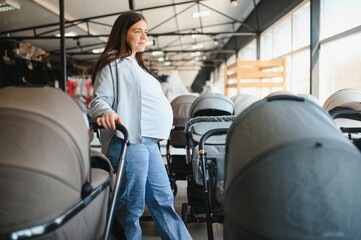 Naklejka premium Young pregnant woman in shop of children goods. The choice for a baby stroller