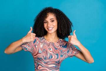 A young, stylish woman with curly hair shows double thumbs up, expressing positivity and charm...
