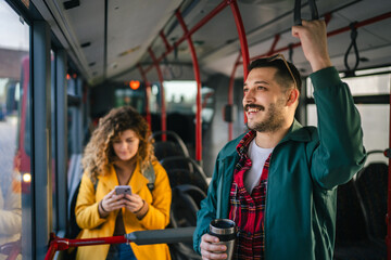man hold thermos and ride at bus in the city and woman use cellphone