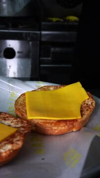 tasty smash burger with melted cheddar resting on a burger bun, part of an artisanal street food cooking scene &ndash; macro food video