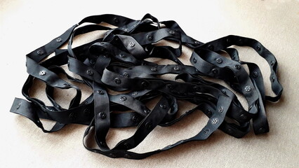 Black ribbon with buttons on a light background. Fastener. Sewing materials.