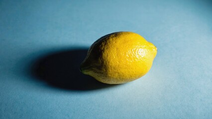 A single lemon sitting on a blue surface, great for decoration or as a prop in your image