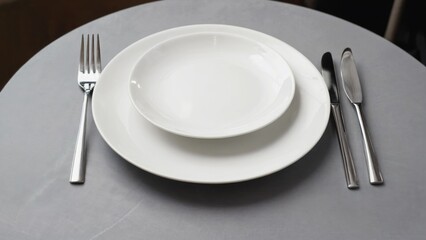A simple table setting with a white plate and matching silverware, ideal for use in lifestyle or commercial photography