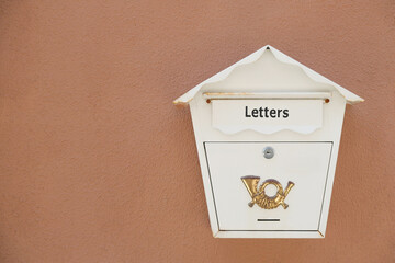 Old white mail box on brown wall outdoors