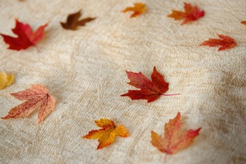 Autumn leaves scattered on a beige textured fabric, showcasing fall colors and textures.