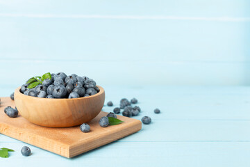 Bowl with fresh bright blueberries on wooden table