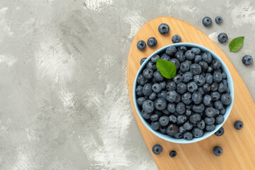 Bowl with fresh bright blueberries on concrete background,top view