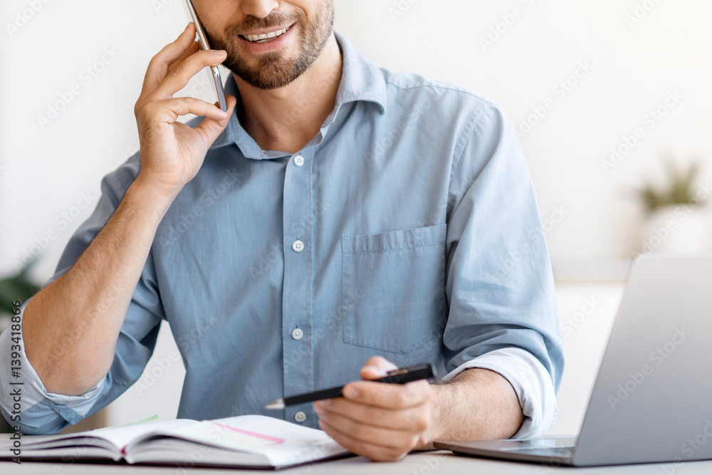 Poster Smiling Businessman Taking Notes While Having Phone Conversation, Sitting At Desk In Modern Office Talking On Cellphone With Client, Checking Business Or Working Schedule In Notepad, Copy Space