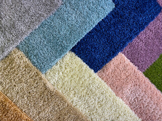 Colorful assortment of textured rugs arranged in a diagonal pattern showcasing various shades and...