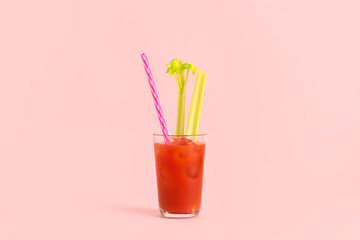 Glass of bloody mary with celery on pink background