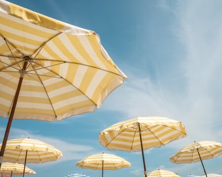 Yellow striped umbrellas under blue sky.