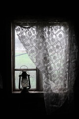 Lampa naftowa widoczna na tle starego okna  © tomo81