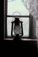 Lampa naftowa widoczna na tle starego okna  © tomo81