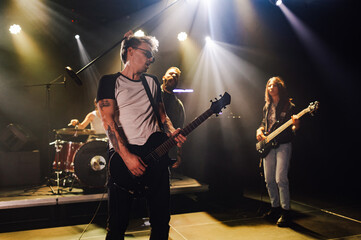 Guitarist performing with band on stage under stage lights