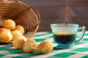 Brazilian cheese bread with coffee, delicious Brazilian cheese bread with a cup of coffee and accessories on a rustic table with a green and white checkered tablecloth, selective focus.